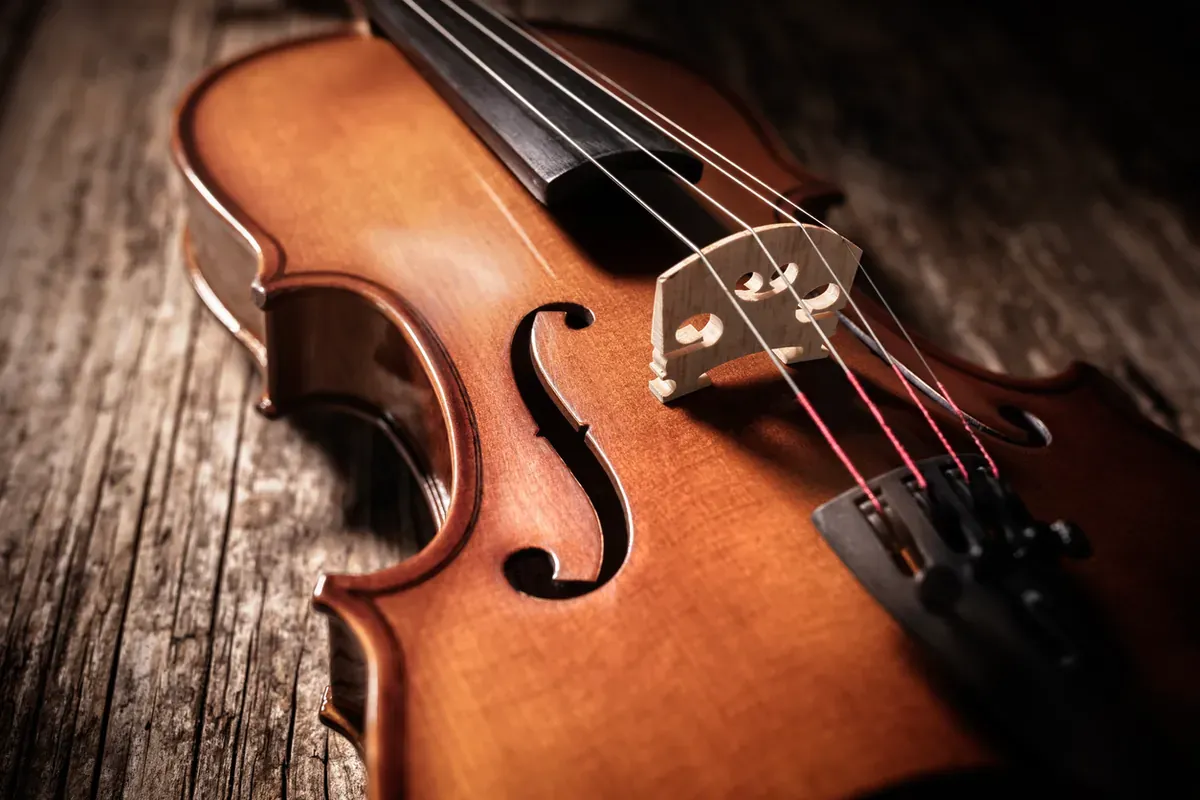An overhead flat lay of a violin, sitting on a rustic wooden table.